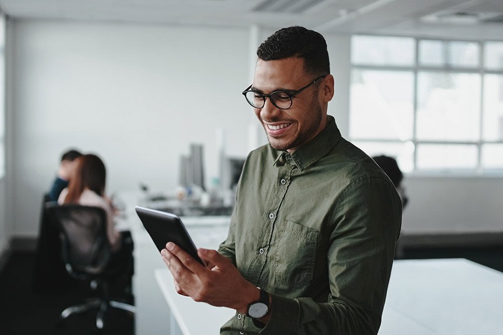 Confident smiling businessman using smartphone in office