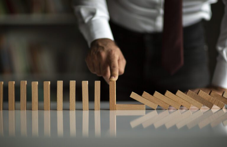 Businessman Stop Domino Effect. Risk Management and Insurance Concept