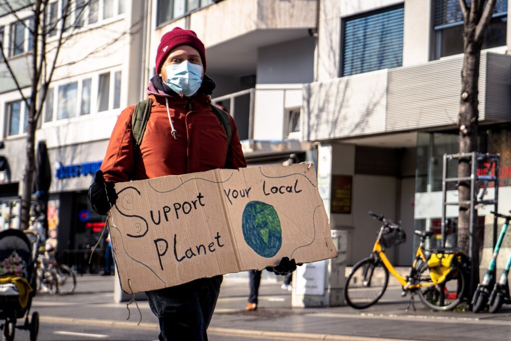 environmental campaign - person at protest with support our local planet sign