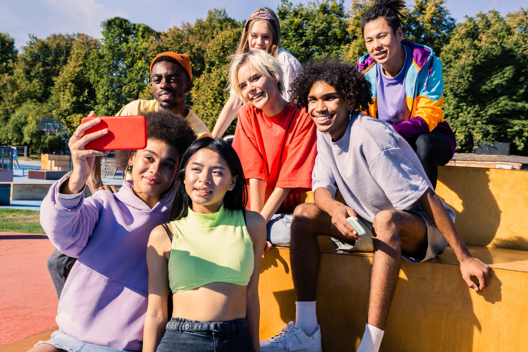 Multicultural group of young friends bonding outdoors and having fun - Stylish cool teens gathering at urban skate park