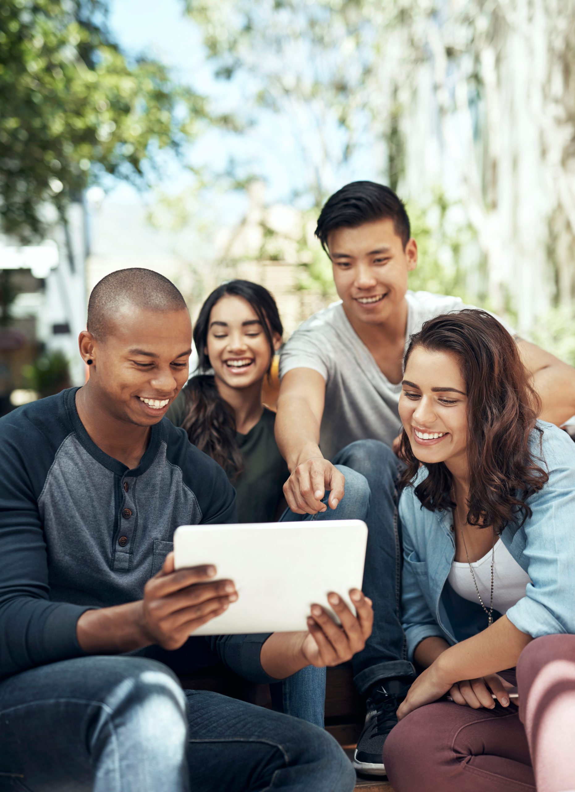 Shot of a group of young men and women using a digital tablet together on campus