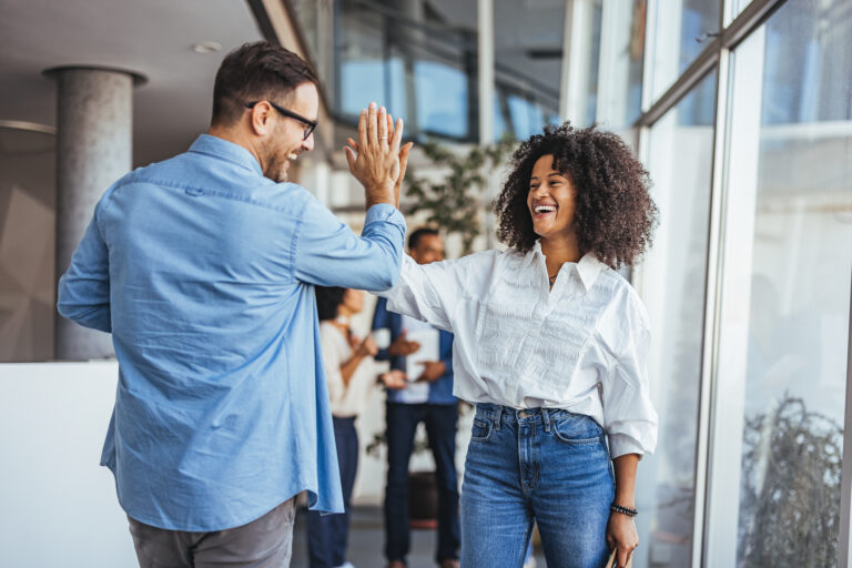 Employees high-fiving in office
